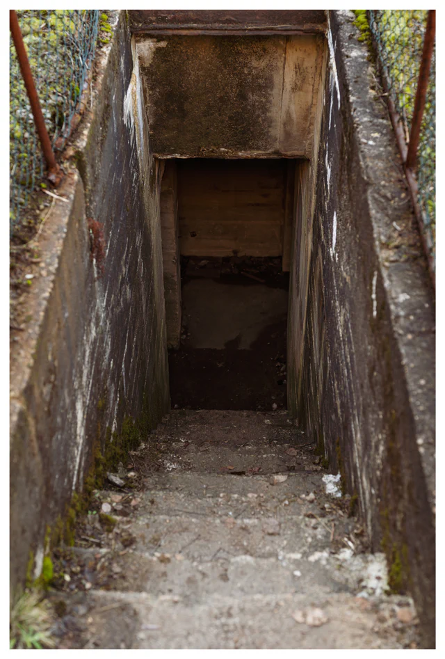 Narrow concrete staircase leading down into an underground tunnel at Hausvikodden Fort, showing part of the interior network beneath the coastal defenses.