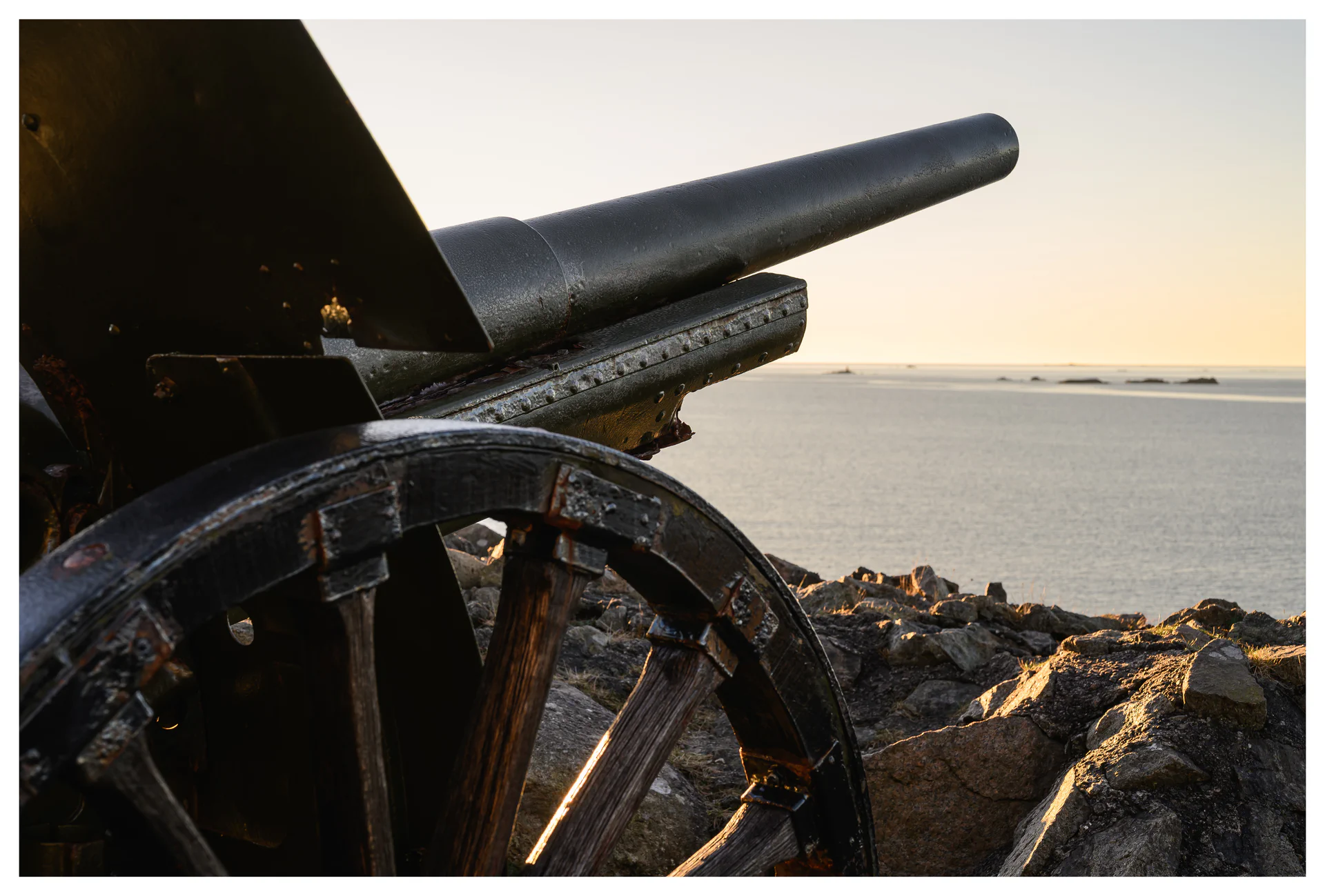 Close-up detail of a coastal artillery cannon at Hausvikodden Fort, with the gun barrel pointing out over the rocky shoreline and sea.