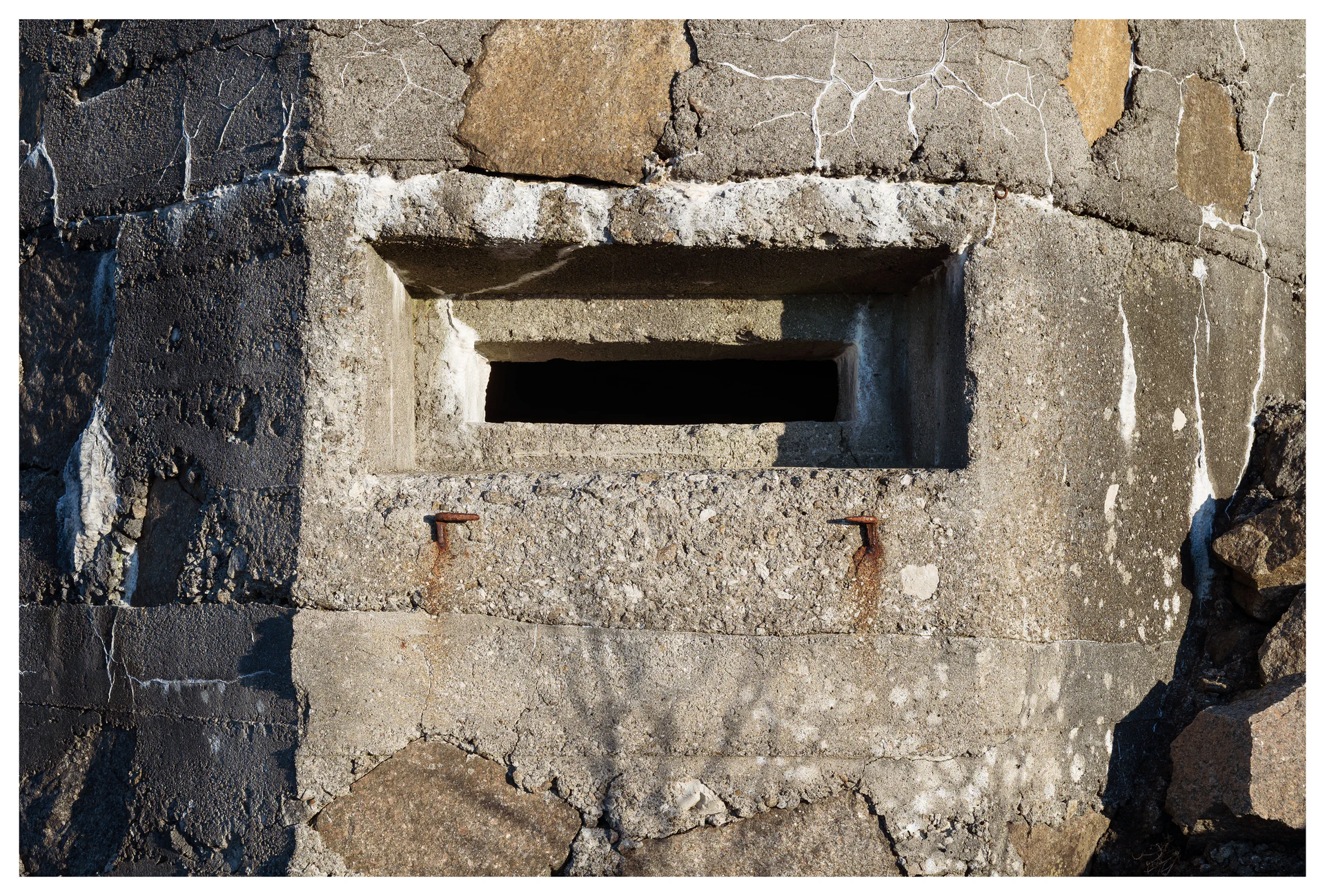 Concrete observation slit at Hausvikodden Fort, showing cracked stonework, rusted bolts and the narrow opening once used for watching the coastline.