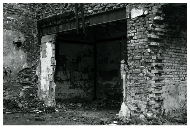 Crumbling brick entrance inside the abandoned Mago C power plant in Eidsvoll, showing damaged walls, exposed structure, and debris scattered across the floor.