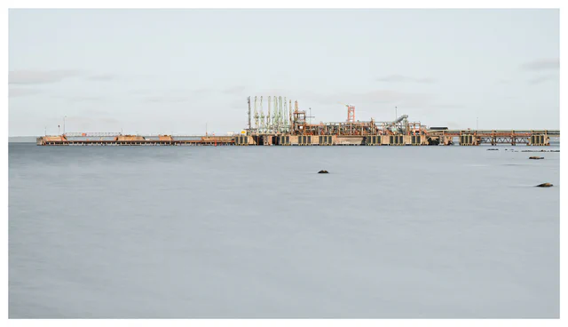 Industrial structure stretching across calm water near Tønsberg, Norway, beneath a pale sky in a long-exposure photograph.