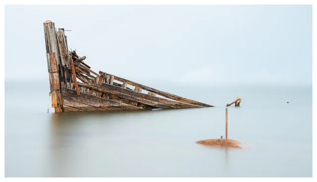 Long-exposure photograph of the wreck of Christiania emerging from calm water at Hvaler, Norway.
